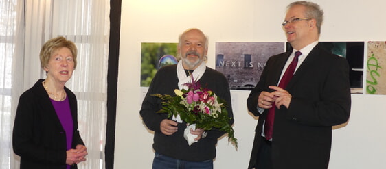 Bernhard Laß (m.) wurde von Rosemarie und Pfarrer Holger Reinhardt bei der Vernissage ein Blumenstrauß als Dankeschön überreicht. (Foto: Ingrid Weiland)