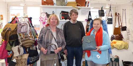 Ulla Nagl, Leiterin des Weltladen-Teams in Lüdenscheid, sowie die ehrenamtlichen Mitarbeiter Wolfgang Letzbor und Christel Schacht als (v.l.n.r.) freuen sich über das Angebot von Ledertaschen und anderen fair gehandelten Produkten in ihrem Weltladen (Foto: Weiland)