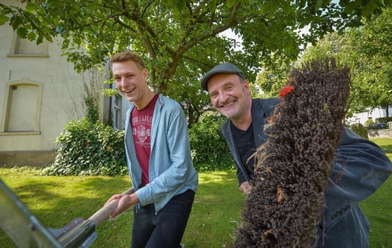 Patrick Schauerte und Guido Raith (v.l.) zeigen, wie es geht: Mit Besen, Schaufel oder Rasenmäher kann es unter freiem Himmel ab sofort wieder losgehen. Die Taschengeldbörse nimmt wieder Anfragen von Senioren an, die sich zum Beispiel Unterstützung bei der Gartenarbeit wünschen.