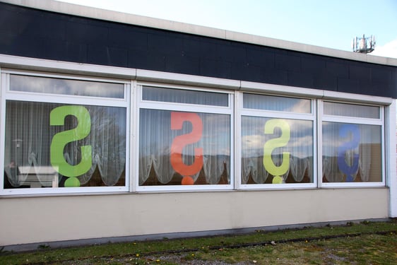 Große Fragezeichen an den Fenstern zur Straßenseite Am Mathagen machen derzeit auf die Aktion "Fenster-Galerie" aufmerksam. In den kommenden Monaten sollen die Fenster während der Umbauphase der Kirche in einen Dritten Ort thematisch gestaltet werden. (Foto: Jakob Salzmann)