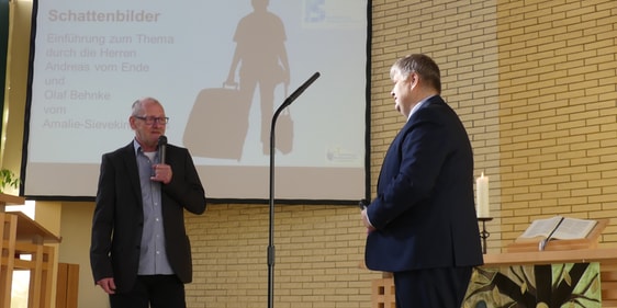 Andreas vom Ende, Leiter der Wohnungslosenhilfe im Amalie-Sieveking-Haus in Lüdenscheid (r.), interviewte Olaf Behnke (l.), der dank der Wohnungslosenhilfe eine Veränderung erfahren hat – vor dem Schattenbild, das einen Menschen zeigt, der bei der Wohnungslosenhilfe Aufnahme findet (Foto: Ingrid Weiland)