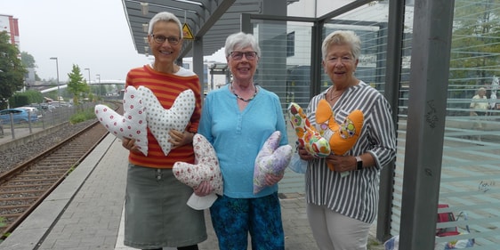 Karin Fuhrmann (Mitte), Leiterin der Nähgruppe des CVJM Lüdenscheid-West, und zwei Mitglieder dieser Gruppe, Rita Scheel (l.) und Christa Schnippering (r.), mit selbstgemachten Herzkissen, die sie vom Lüdenscheider Bahnhof aus ins Wittner Brustzentrum brachten. (Foto: Ingrid Weiland)